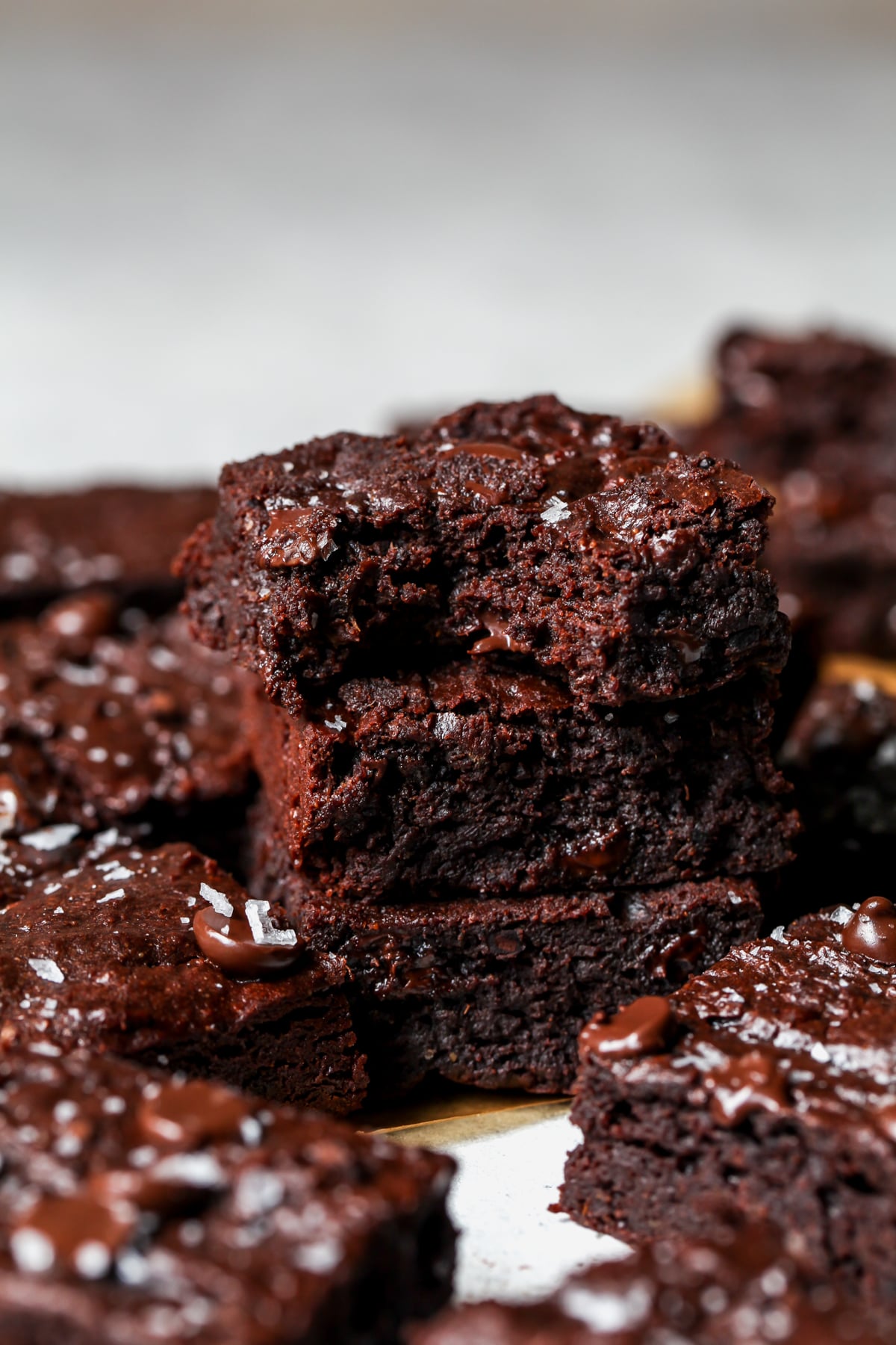 Sweet brownies stacked on top of each other with the top brownie showing a bite taken out to reveal the fudgy inside textire.