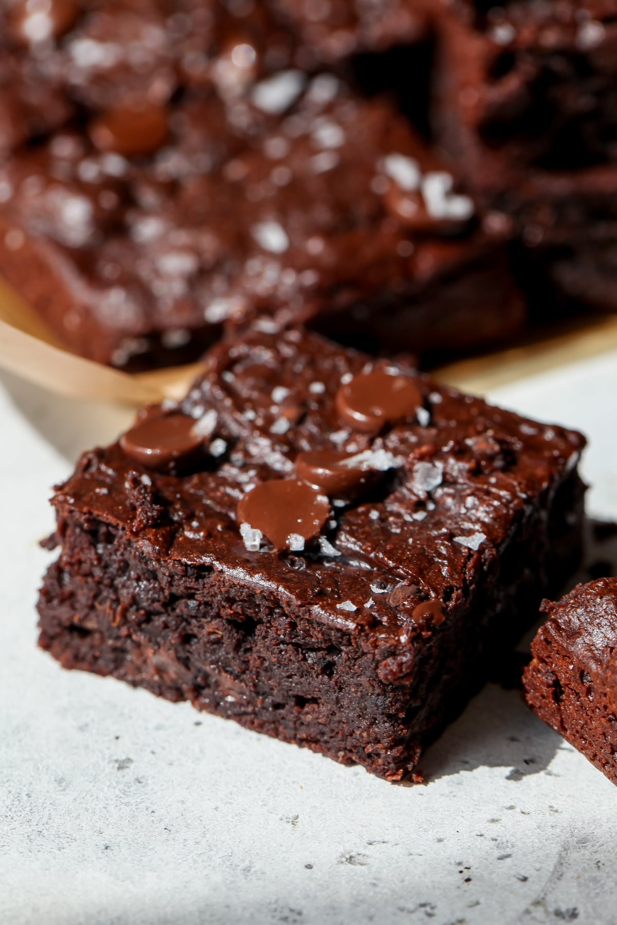 A single square of a sweet potato brownie topped with flaky salt on a gray surface.