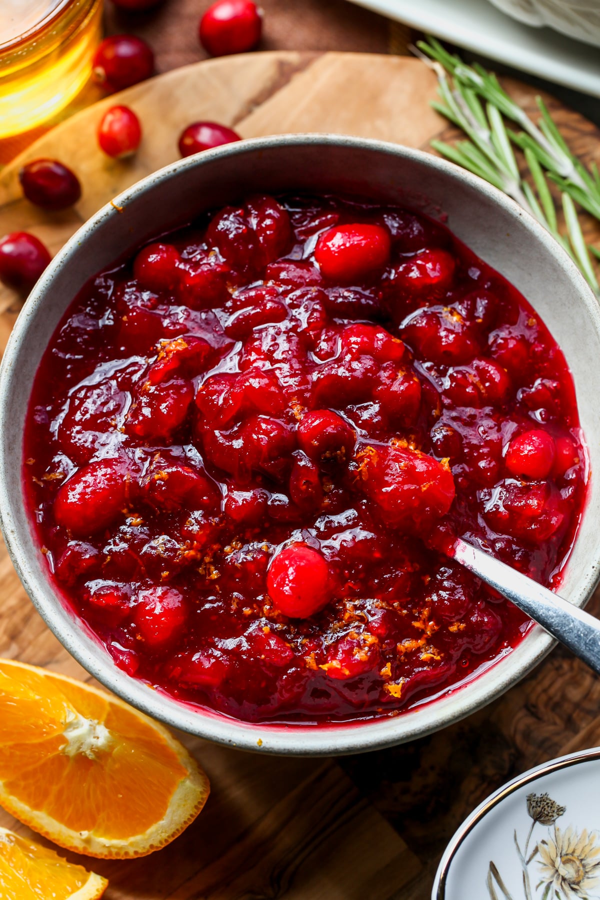 A spoon digging into a small white bowl of cranberry sauce.