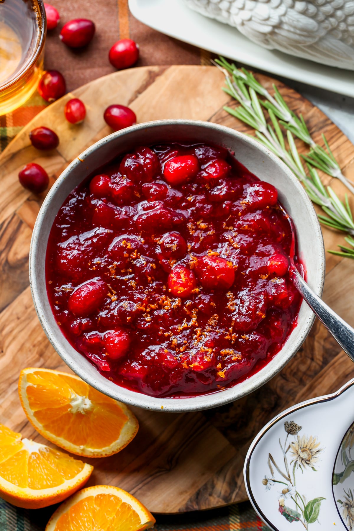 Cranberry Sauce with Orange and Rosemary styled in a white bowl on a round wooden board.