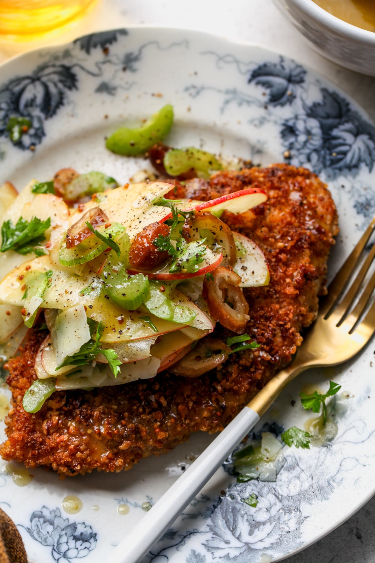 Pecan-Crusted Chicken with Apple-Celery Salad arranged on a blue and white floral dinner plate.