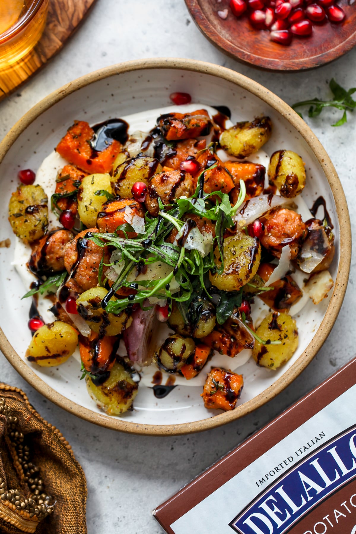 Sheet pan gnocchi with sausage served over whipped ricotta in a white bowl.